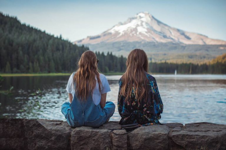 Two girls sitting by lake