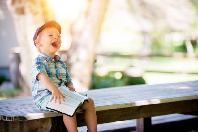 Boy reading and laughing outside