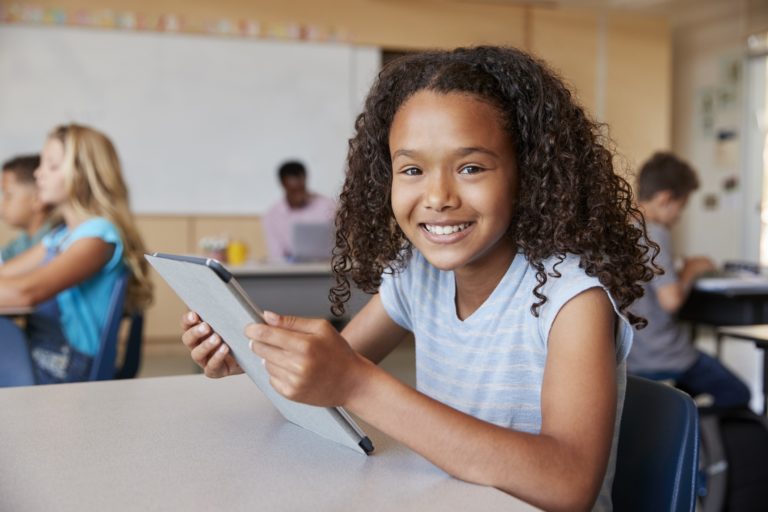 Girl using tablet in school class smiling to camera close up